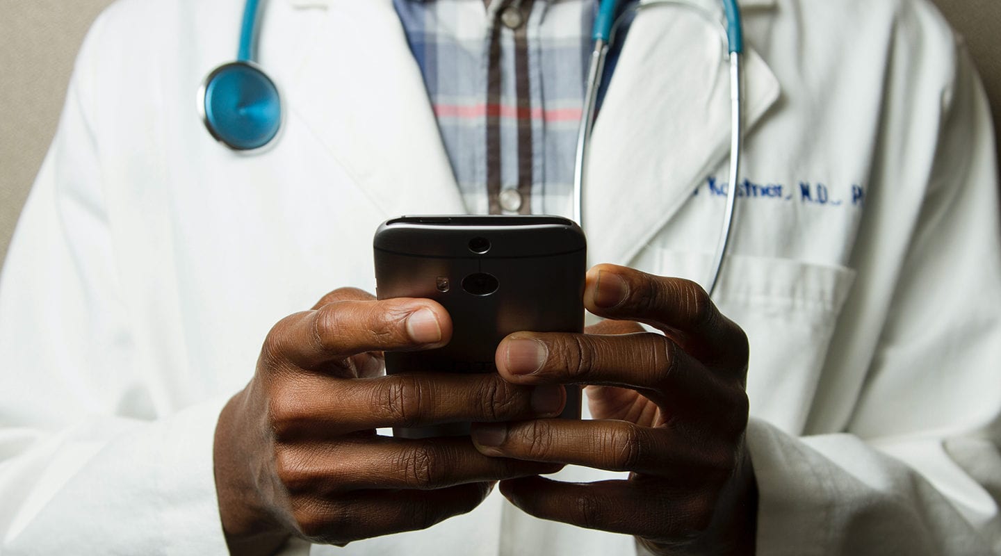 Black doctor holding a cell phone