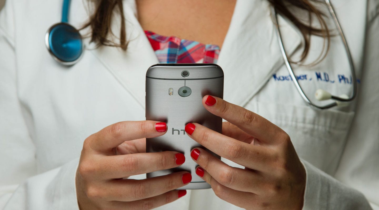 White female doctor holding cell phone