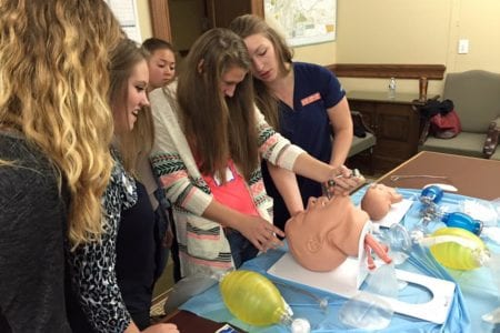 HOSA student learning how to intubate with an instructor looking on