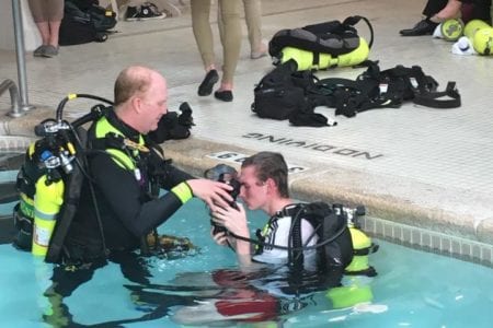 Male HOSA student donning SCUBA gear with a SCUBA Search and Rescue trainer in a pool